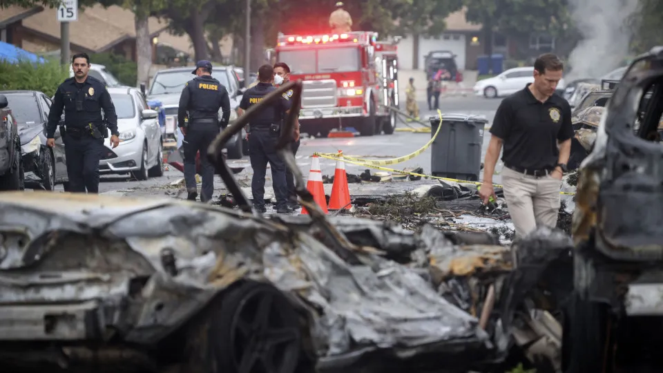 #PARA TODOS VEREM: Imagem mostra destroços do Jato executivo no chão, com veículos incendiados e alguns policiais caminhando sobre os escombros.
